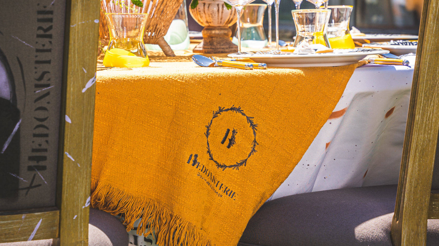 Tissage orange avec le logo de l'agence événementielle Hédonisterie sur une table dressée